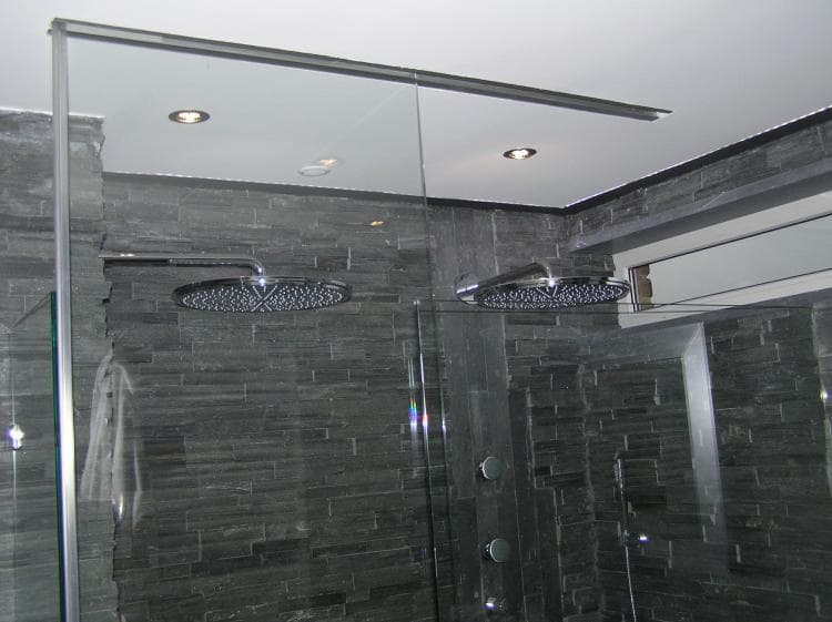 Une Salle de bain avec une paroi de douche en verre translucide suspendue a un rail dont la technique est totalement invisible.